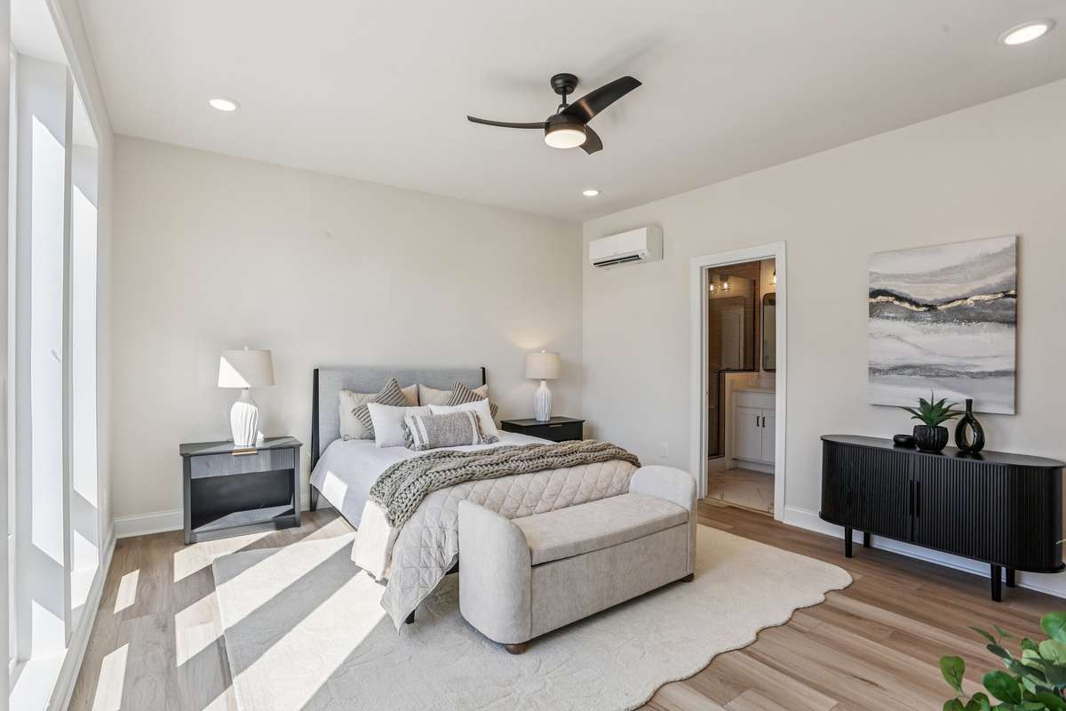 Spacious primary suite with hardwood floors and recessed lighting, enhanced by oversized windows that flood the room with natural light.