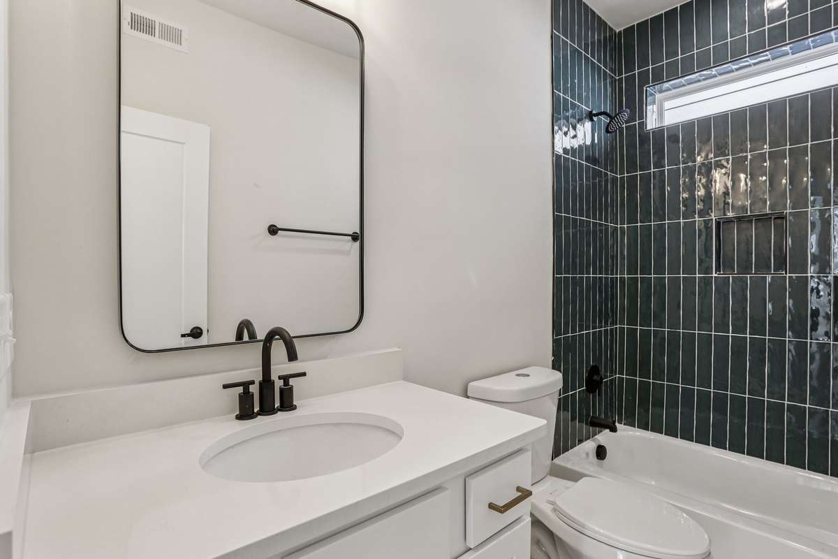 Designer-tiled tub paired with a spacious, full-width vanity.