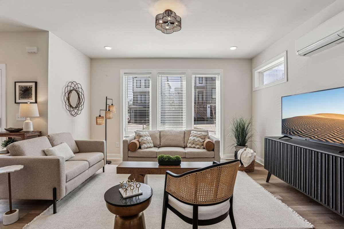 Bright living room with hardwood floors and large windows that bring in plenty of natural light. The space opens comfortably into the dining area and kitchen, making it ideal for everyday living and entertaining.
