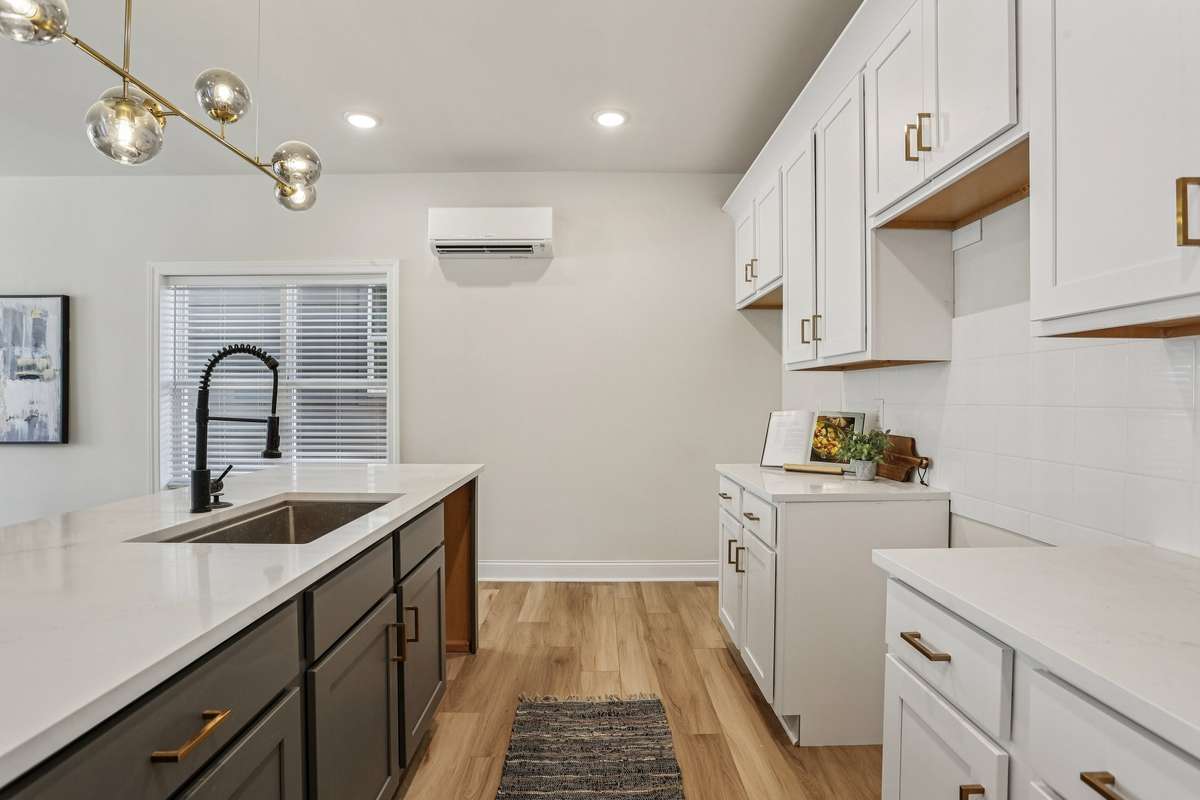 The kitchen offers a spacious center island with seating, quartz countertops, and contrasting cabinetry for added character. It opens directly to the main living area, making it easy to stay connected while cooking or entertaining.