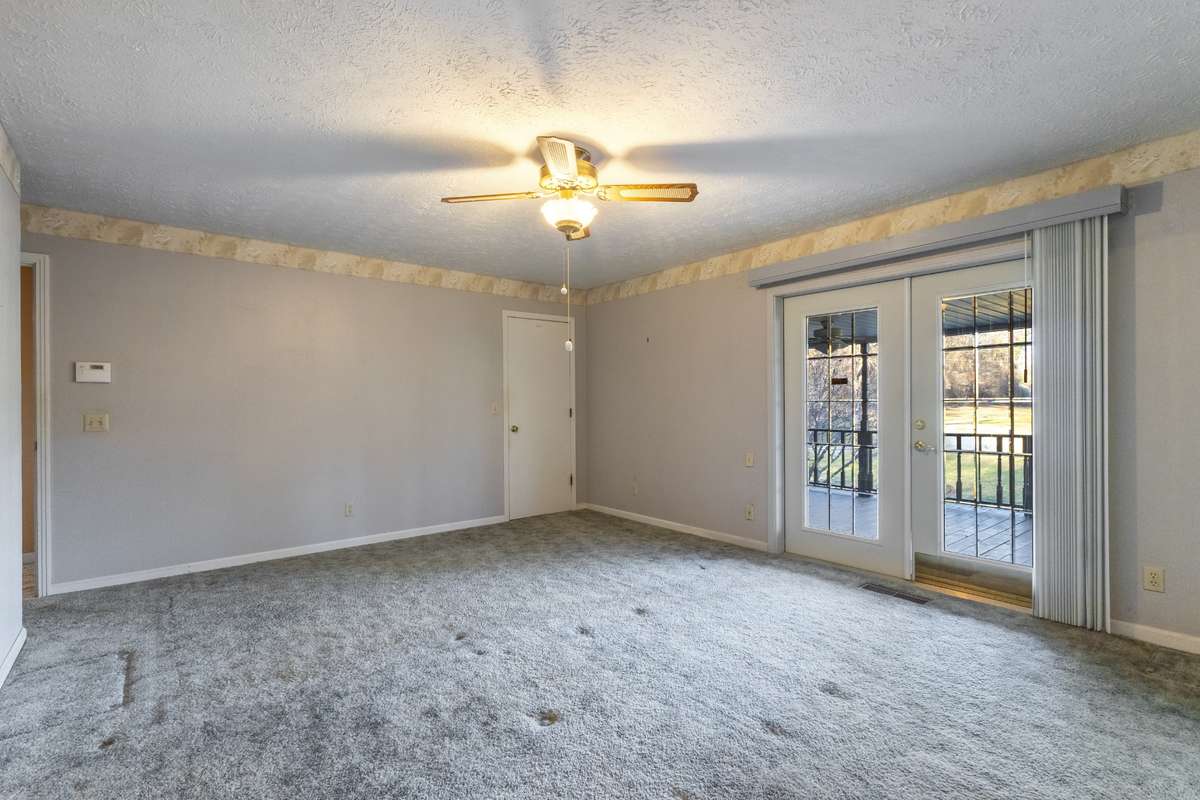 Glass doors open to front porch with view of tree lined driveway