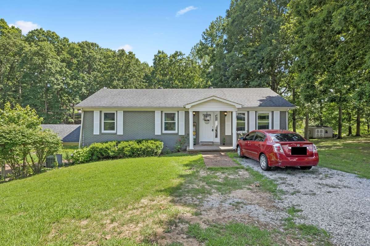 Front of home with upper gravel parking area
