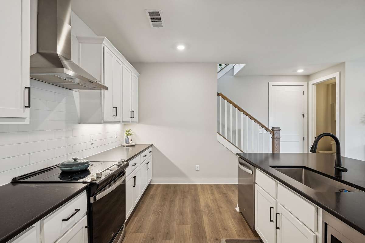 Spacious kitchen with tile backsplash, granite counters, stainless appliances, and garbage disposal.