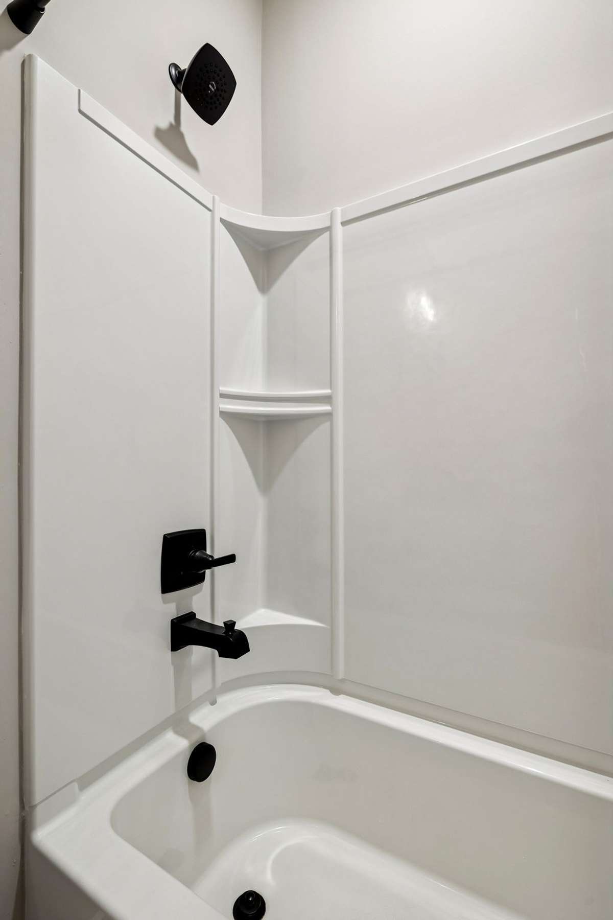 Guest bath tub/shower combo with built in shelving in the surround.