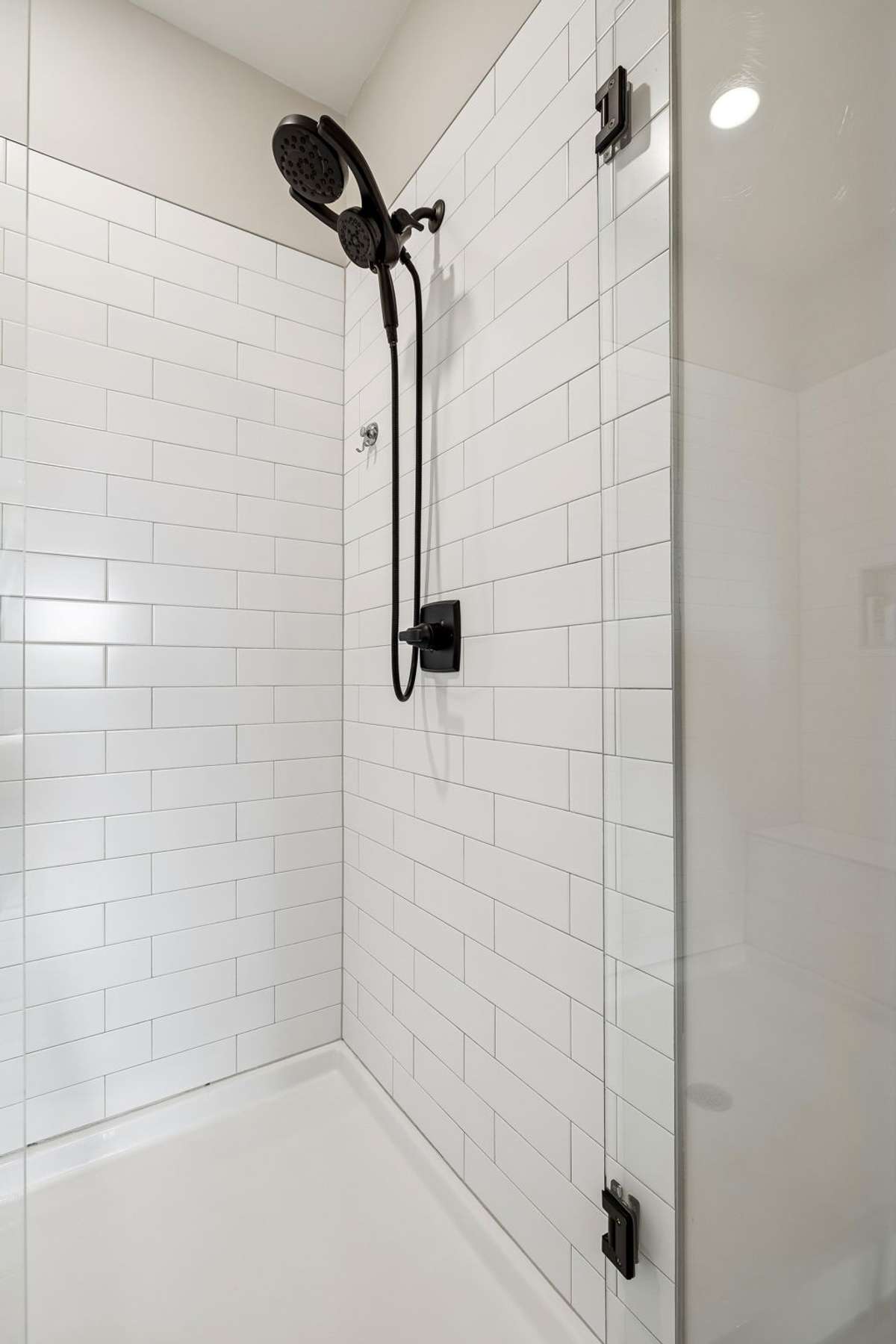 Walk in shower with frameless glass door, tile surround, and tile bench.