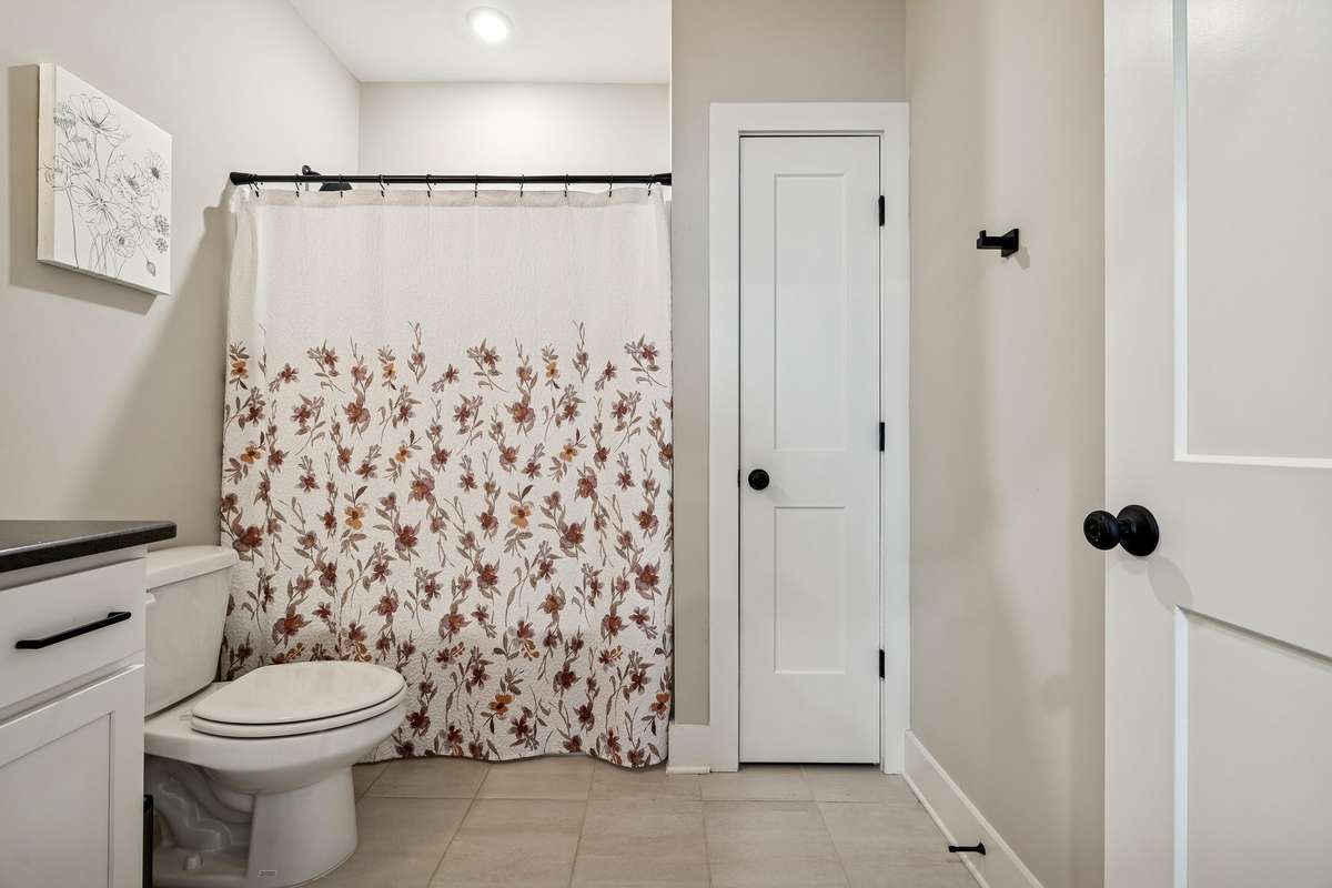 Upstairs guest bath has a linen closet, tile flooring, and a vanity for additional storage.