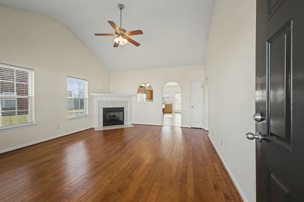 View of the Living Room from the front door.  Nice hardwood flooring and gas fireplace.  Tall ceilings with fan.