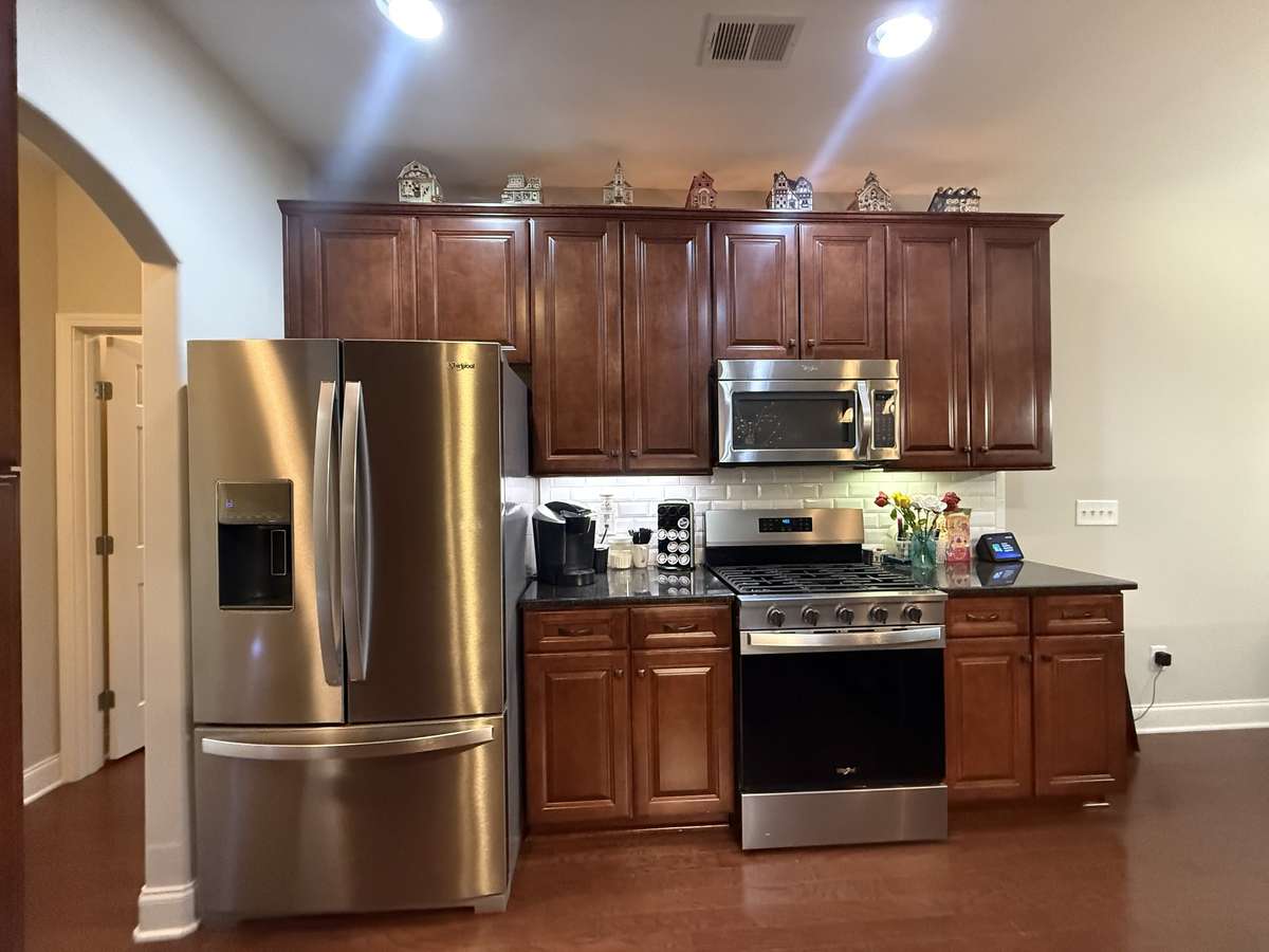 The kitchen is equipped with granite countertops and new stainless-steel appliances, including a gas range.