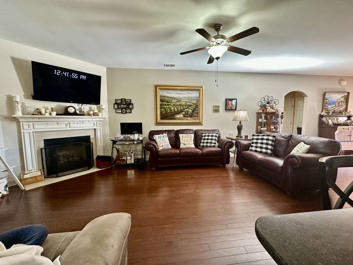 The spacious 23x14 Living Room showcases a beautiful gas fireplace with a white mantle and flows seamlessly into the eat-in kitchen with bar-top seating, creating an inviting space for everyday living and entertaining