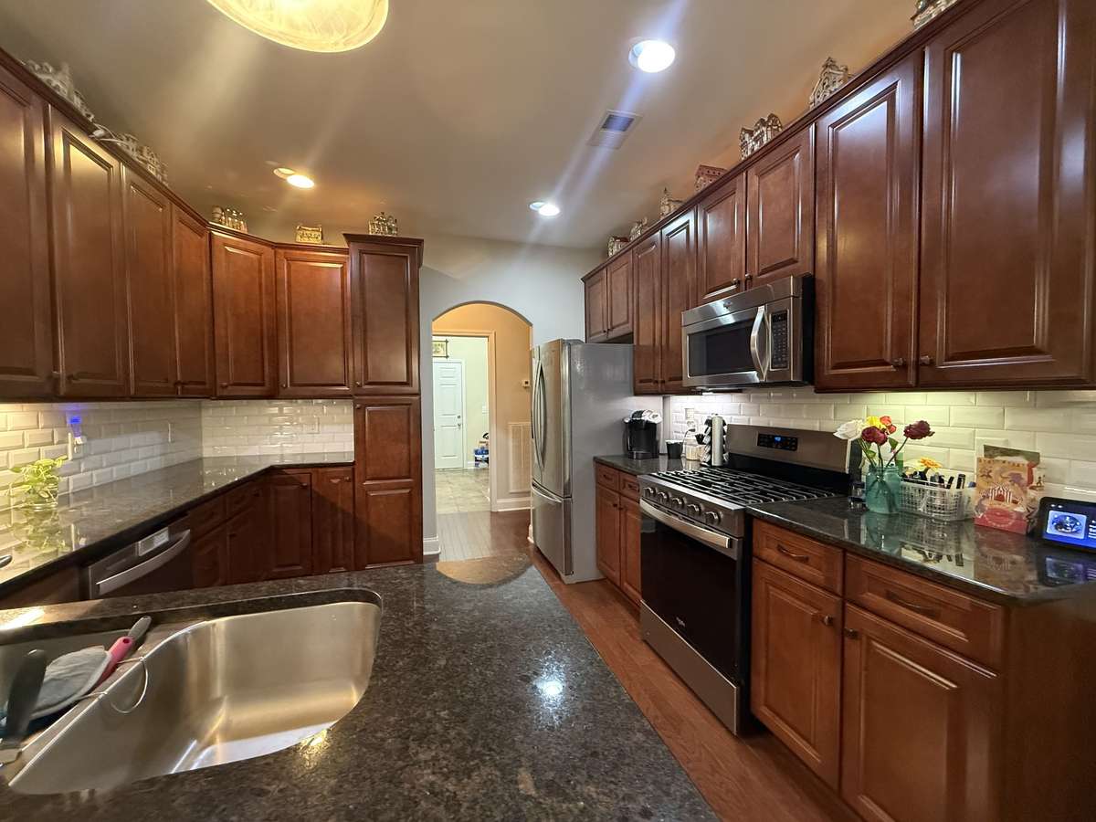 The kitchen is equipped with granite countertops and new stainless-steel appliances, including a gas range.