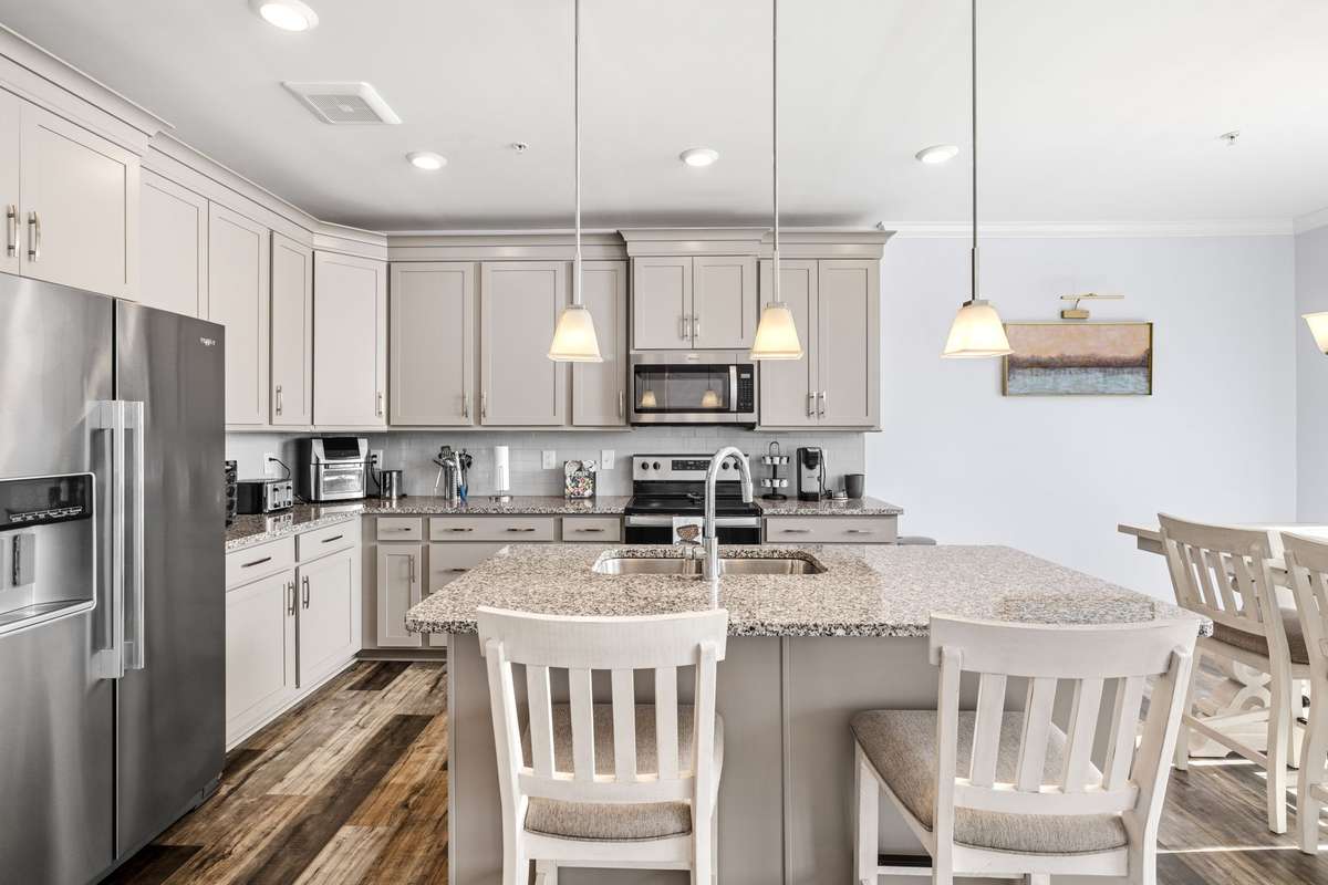 Spacious kitchen with a large center island, double sink, and stylish pendant lighting that anchors the space. Open layout with generous counter space and cabinetry makes it ideal for everyday living and entertaining.