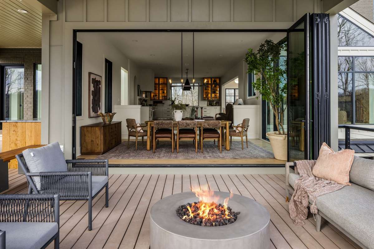 Expansive covered terrace featuring a central fire pit and fully retractable glass doors, creating a seamless transition between indoor dining and outdoor living spaces.