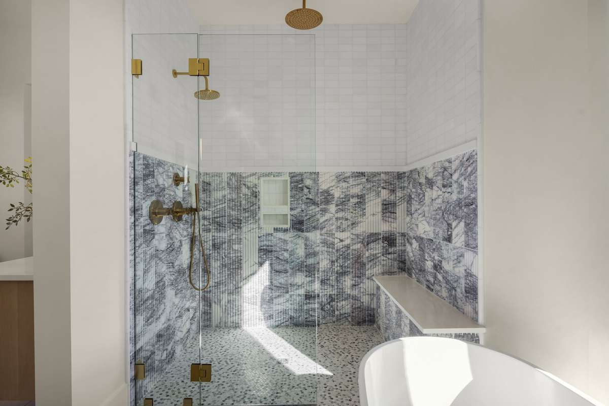 A spa inspired primary shower featuring sculptural tilework and elevated finishes throughout.