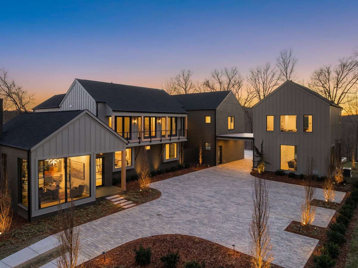 Front courtyard view showcasing the home’s refined modern exterior, thoughtfully arranged living wings, and a spacious paved motor court designed for both everyday convenience and elegant arrivals.