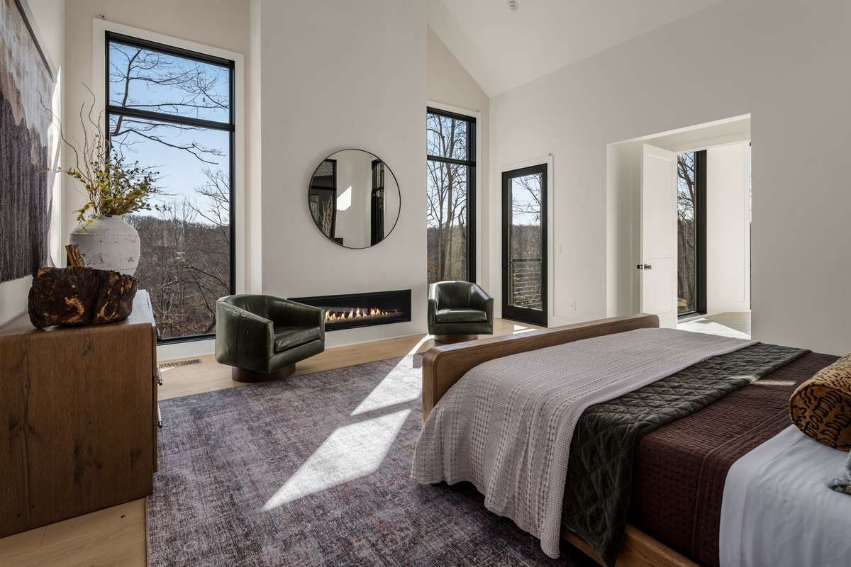 Primary suite fireplace creating a warm and inviting focal point, complemented by soaring ceilings, expansive windows, and tranquil views of the surrounding landscape.