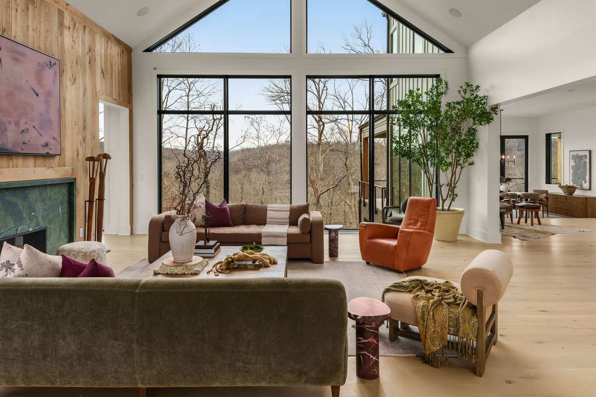 Wide living room view highlighting the open layout, thoughtful furniture placement, and the seamless flow between gathering spaces, all framed by expansive windows and natural light.