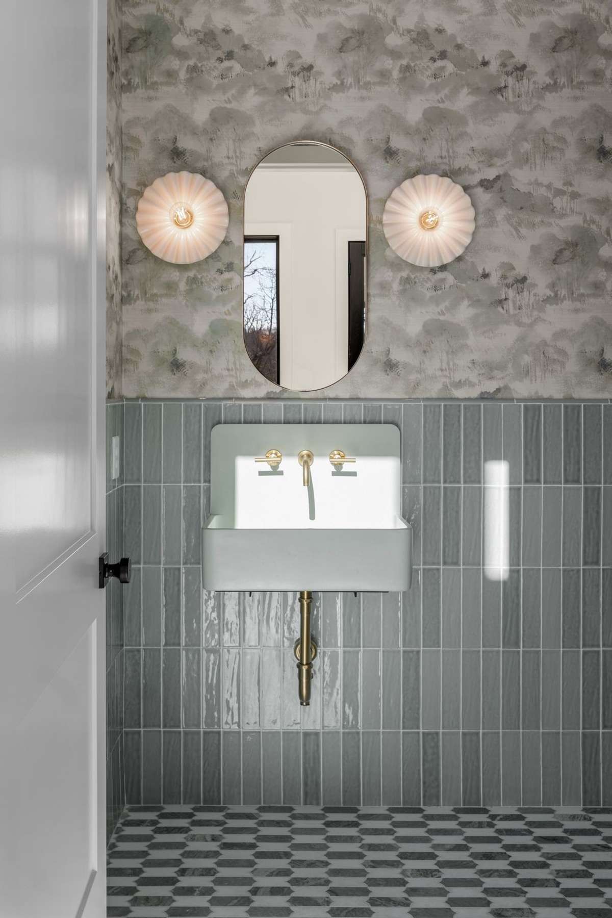 A moody, design forward powder bath layered with custom wallpaper, sculptural lighting, and timeless finishes.