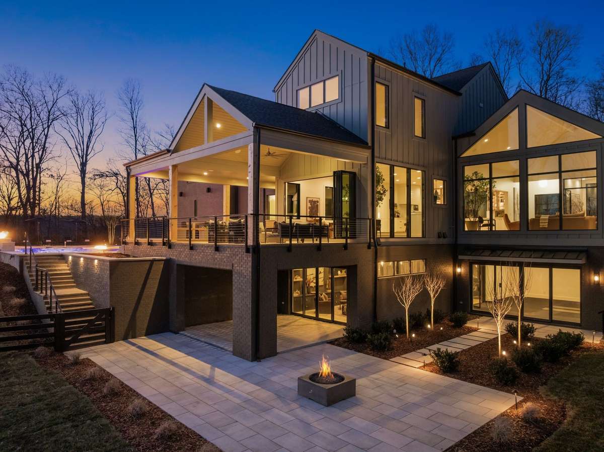 Architectural rear elevation highlighting layered indoor outdoor living, expansive walls of glass, and refined exterior lighting that accentuates the home’s scale and modern design.