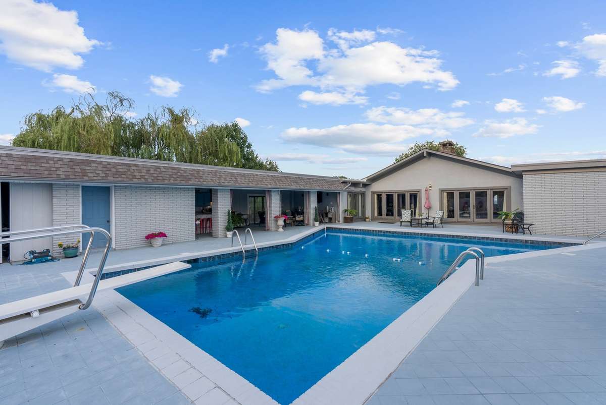 View of house around the pool, this area has a brick wall around it.