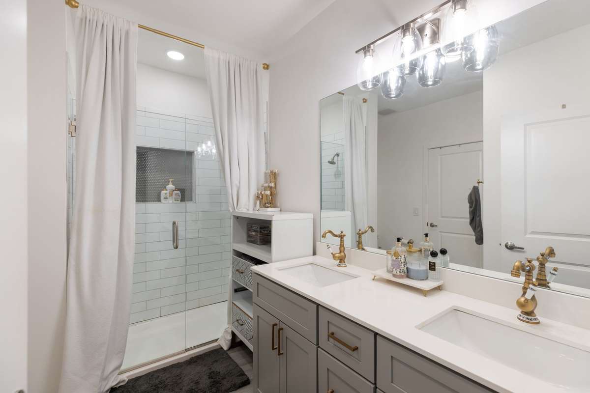 Spacious primary bathroom with glass shower and double vanities