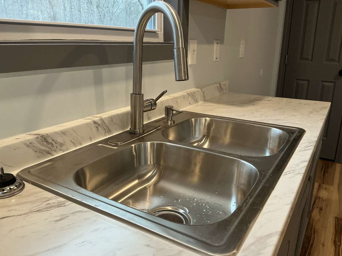 Double stainless kitchen with a gooseneck faucet.