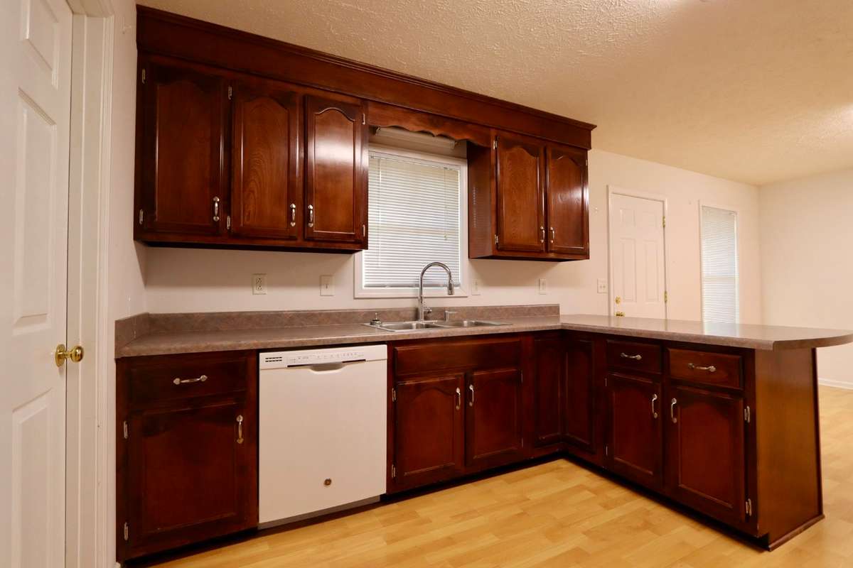 Charming Kitchen with Whirlpool Gas Stove, GE Dishwasher, GE Refrigerator, Coveted Cabinet Space, Lovely Laminate Flooring, and Pantry