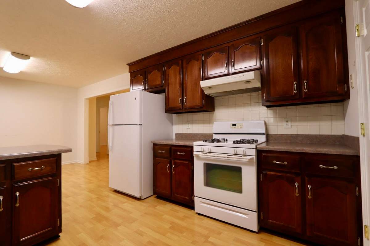 Charming Kitchen with Whirlpool Gas Stove, GE Dishwasher, GE Refrigerator, Coveted Cabinet Space, Lovely Laminate Flooring, and Pantry