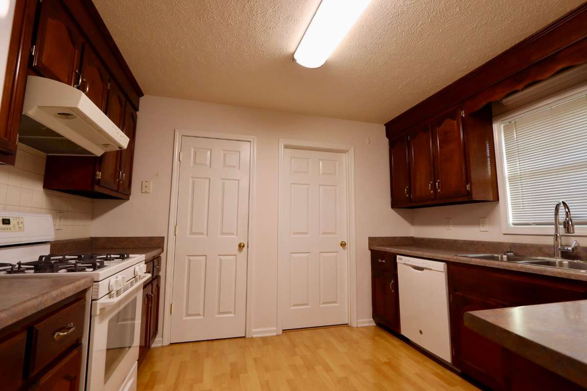 Charming Kitchen with Whirlpool Gas Stove, GE Dishwasher, GE Refrigerator, Coveted Cabinet Space, Lovely Laminate Flooring, and Pantry