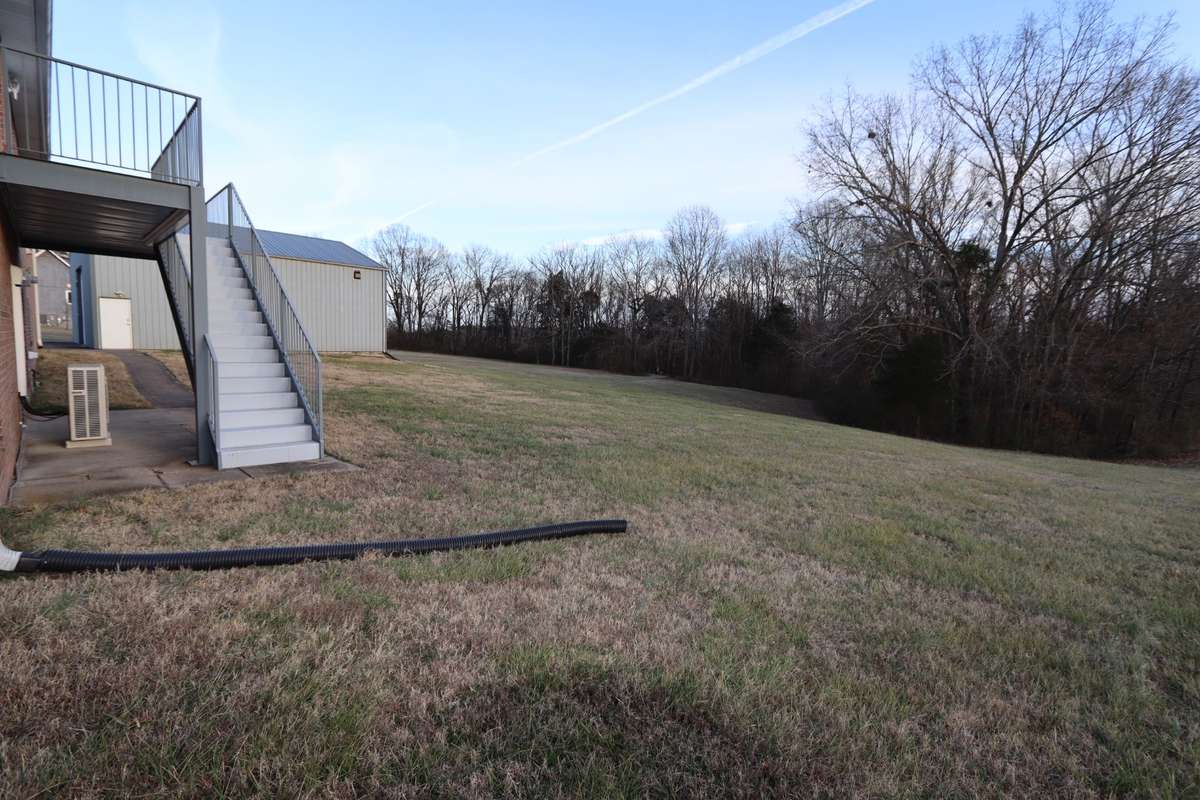 Beautiful Backyard View of Deck/Stairs, Lower-Level Covered Patio and Tree Lined Lot