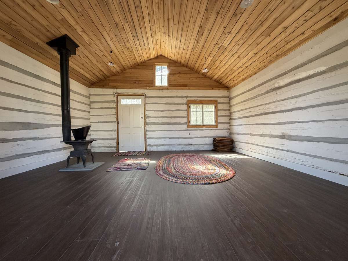 Inside features a wood burning stove, LVP flooring, solar lighting and gorgeous wooden ceiling