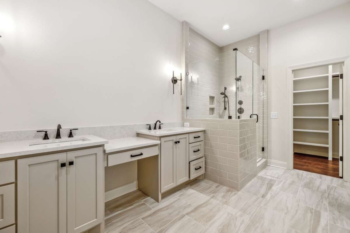 Primary bathroom features quartz counters, vanity seating area, double vanities