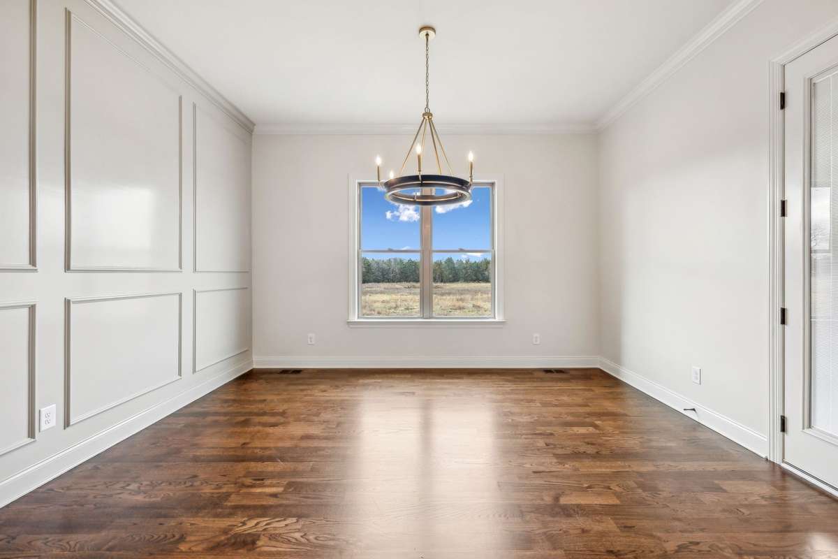 Dining room features trim accent wall, window to backyard, and door to covered porch