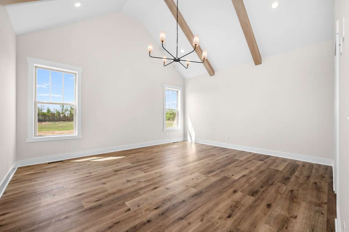 Primary bedroom features designer lighting, wooden beams and is located on the rear of the home for privacy.