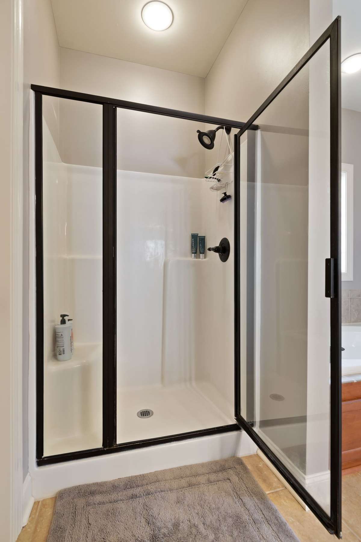 A separate glass-enclosed shower offers a clean, modern design with dark trim accents.