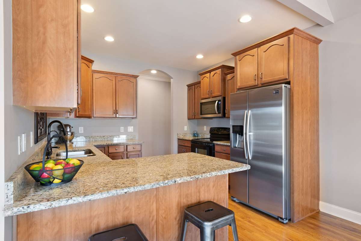 The kitchen features warm wood cabinetry, granite countertops, and recessed lighting throughout.