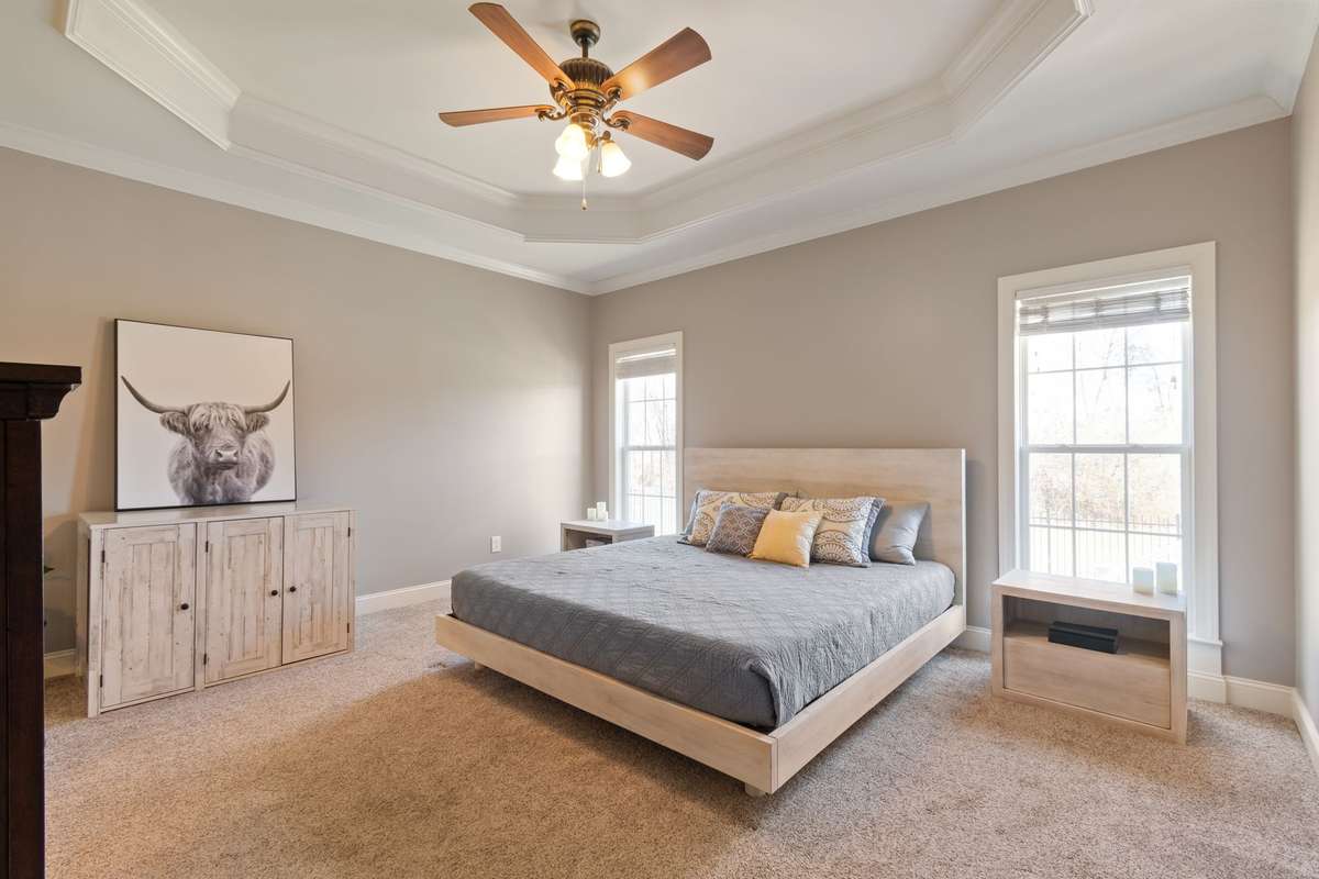 The primary bedroom features a tray ceiling with crown molding and large windows that bring in plenty of natural light.