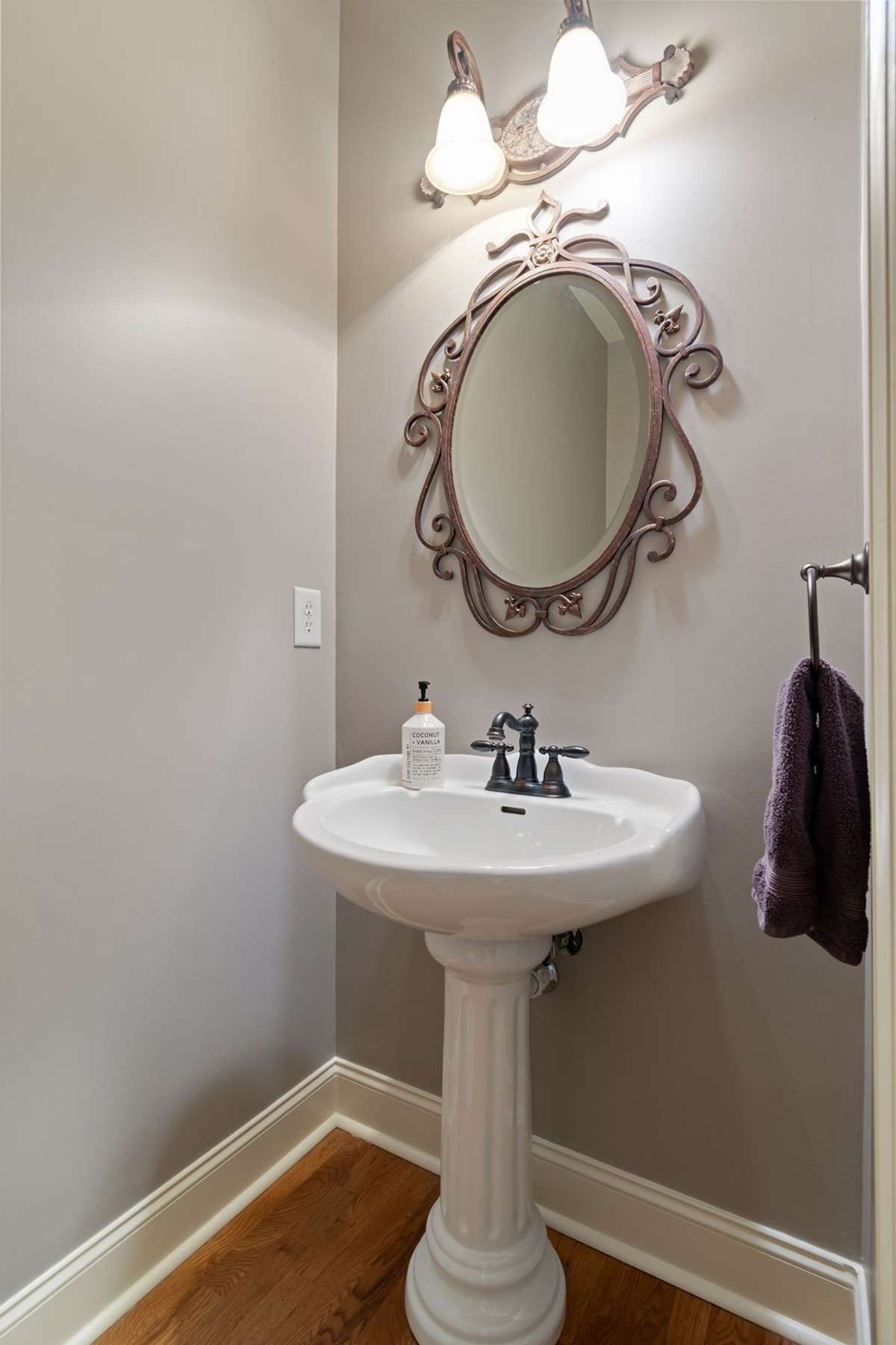A conveniently located half bath features a pedestal sink and neutral finishes.