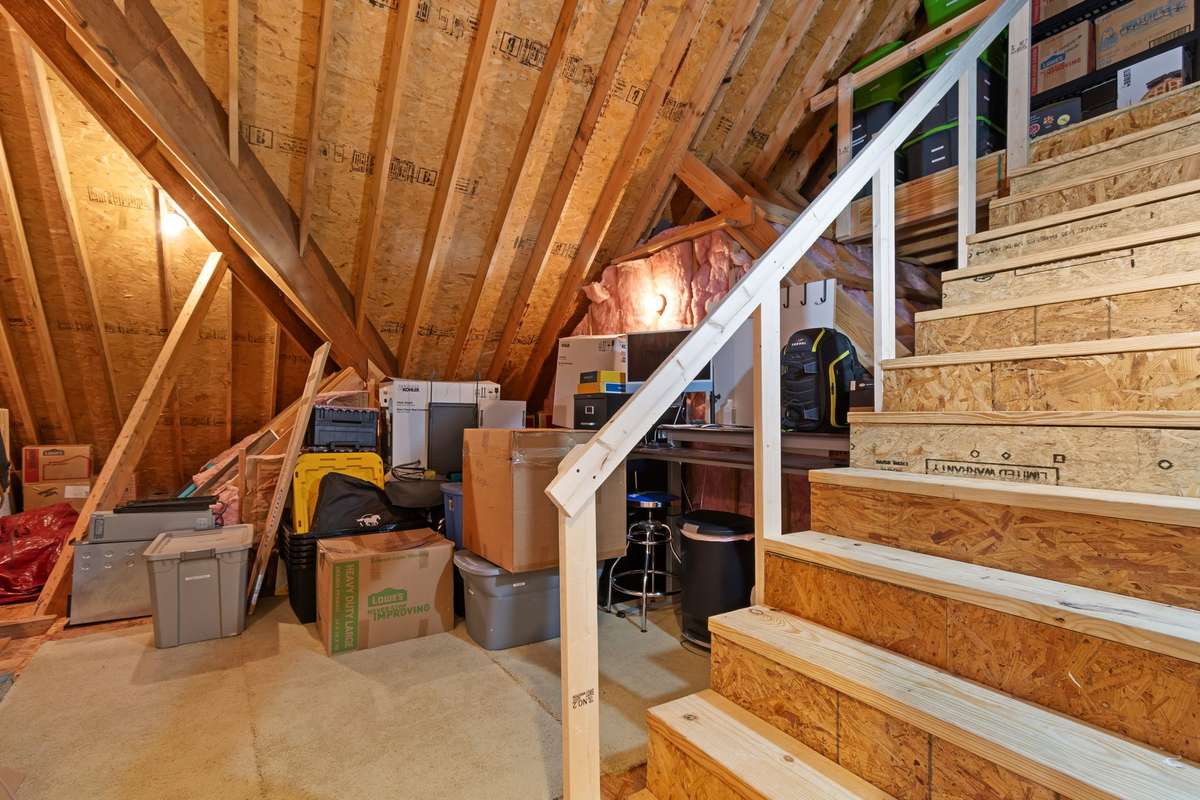 This unfinished attic space provides substantial storage capacity with exposed framing and lighting.