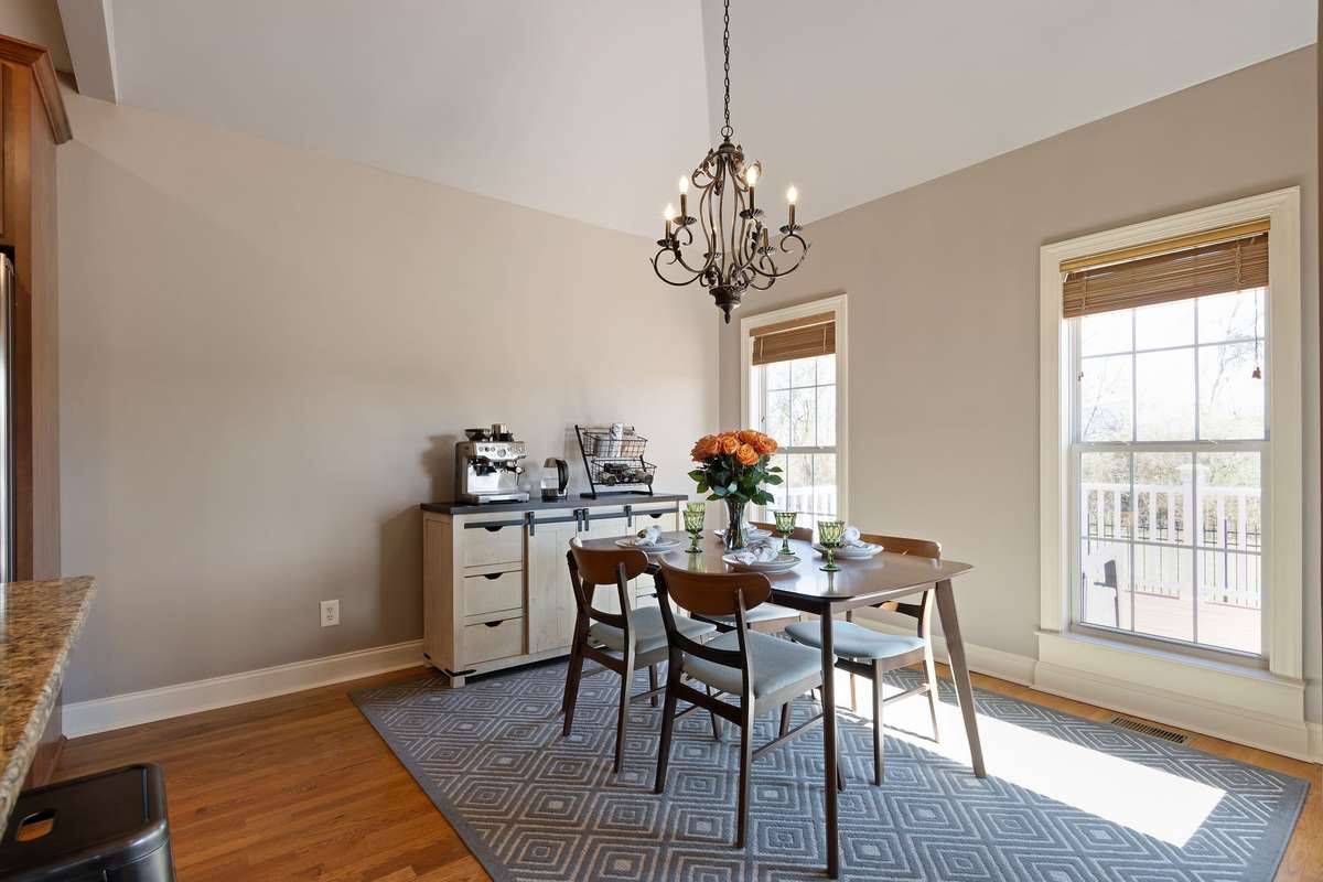 The dining area features hardwood floors, a vaulted ceiling, and a decorative chandelier that anchors the space.