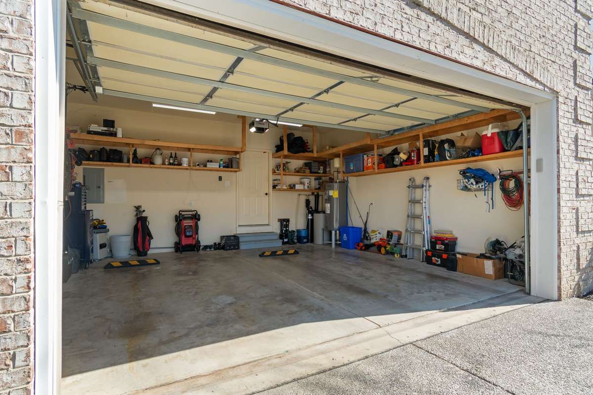 The two-car garage features built-in shelving and ample space for flexible storage.