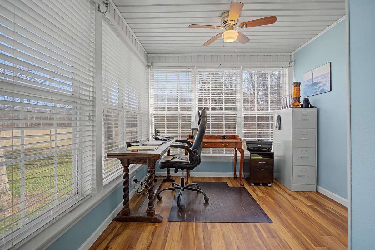 Office area located in front sunroom with wall of windows