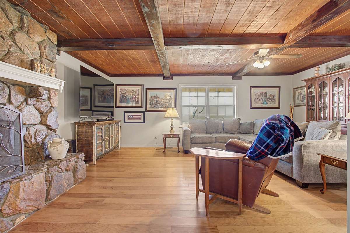 Another view of family room with stone fireplace wood ceiling and hardwood flooring