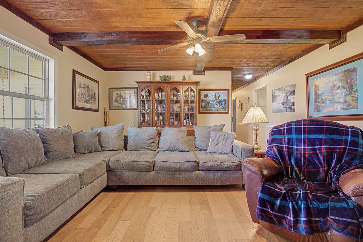 Spacious family room with wood coffered ceiling, ceiling fan and hardwood flooring