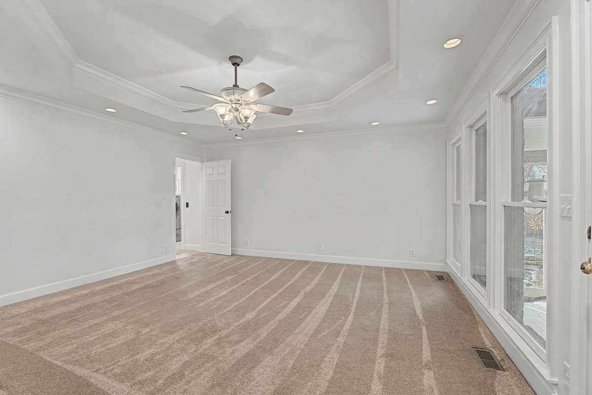 The newer primary suite is off of the dining room and has a tray ceiling with recessed lighting. It overlooks the sunroom.