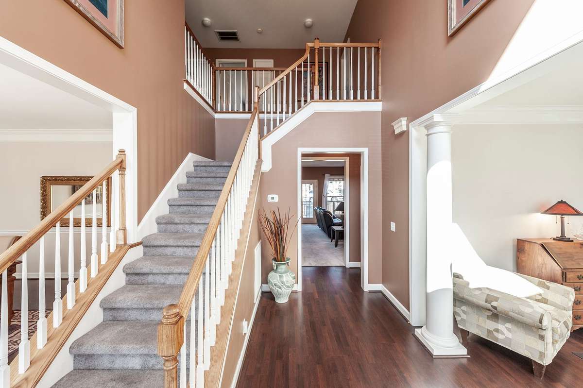 This dramatic two story entry foyer offers a luxurious entry point adding to the elegance and grandeur of this home. Offering dual staircases - this front staircase leads to the upper level with a balconey overlooking the formal entry.