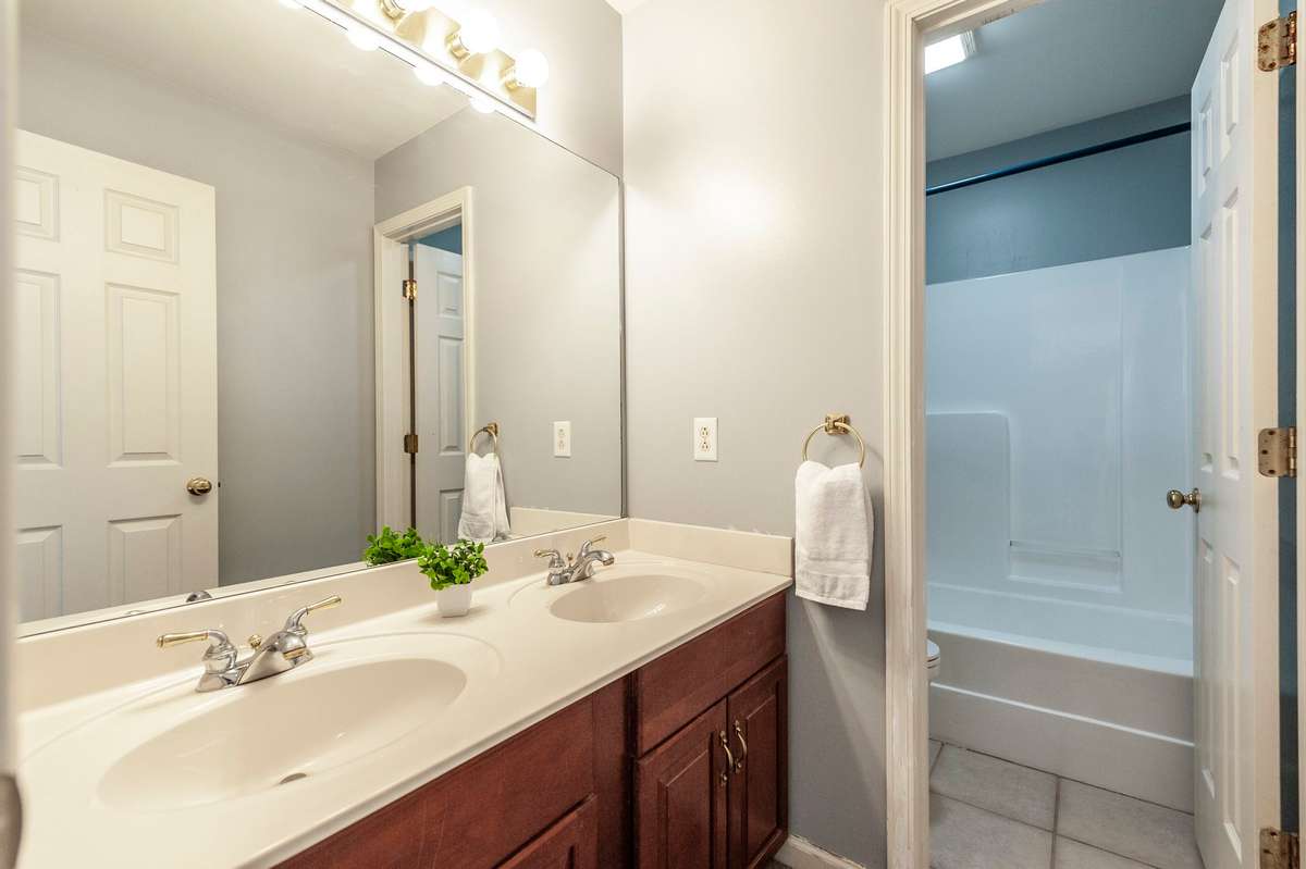 Secondary bedroom bathroom with dual bowl vanity and privacy door to shower area.