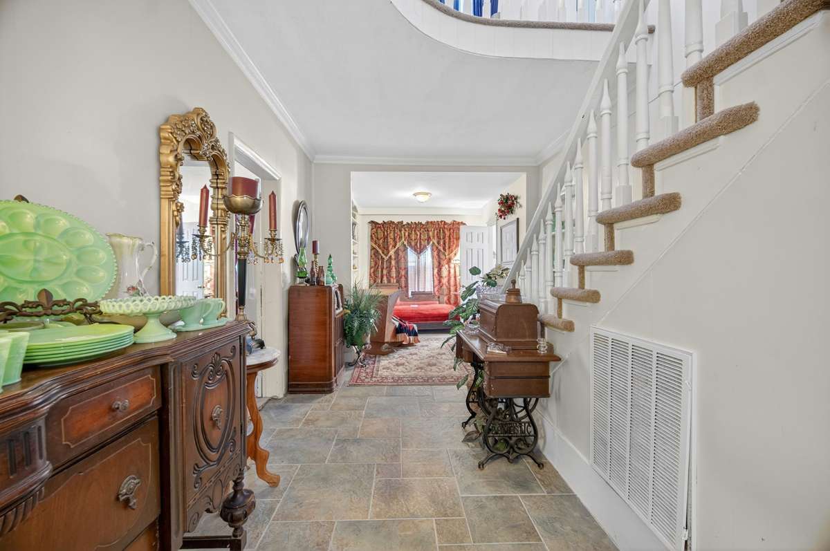 Interior hall showcasing the home’s central staircase, open sightlines, and traditional finishes that connect the main living areas; furnishings may be included, partially included, or removed.