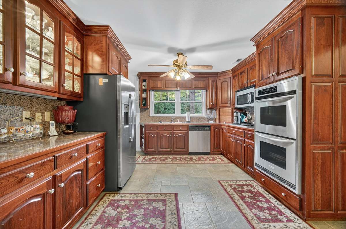 Well-appointed kitchen with abundant wood cabinetry, granite counters, double wall ovens, stainless appliances, and efficient workflow—ideal for cooking and gathering; furnishings may be included, partially included, or removed based on buyer prefere
