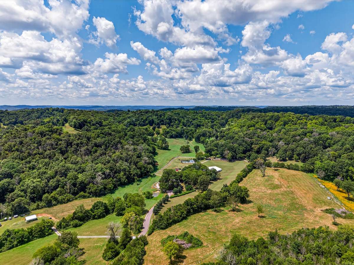 Expansive aerial view highlighting the historic farmhouse, pavilion, pond, and surrounding open fields—illustrating the scale and versatility of this 164± acre estate.