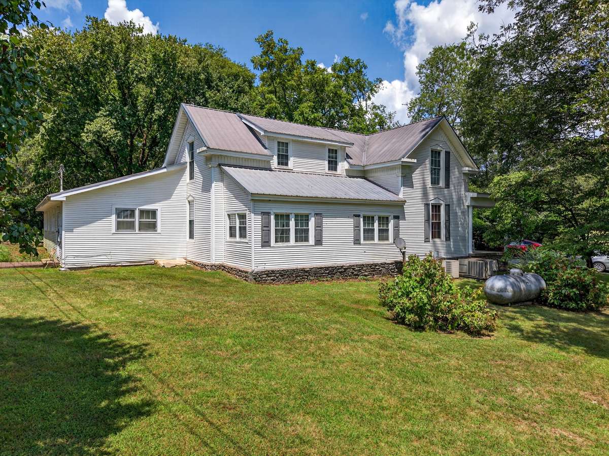 Exterior view of the historic circa 1900 farmhouse, offering timeless character and a commanding presence within the 164± acre estate.